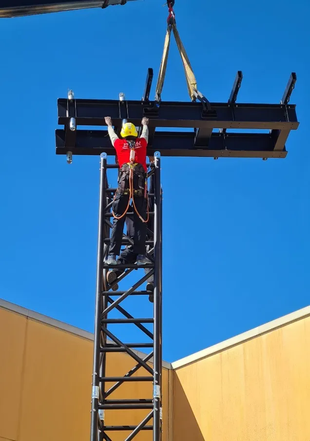 Técnico con arnés y casco guía el elemento superior de una torre LITEC HiPe Q76 suspendido de eslingas