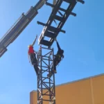 Montaje de una torre de delay LITEC HiPe Q76 de acero con grúa y dos técnicos de rigging en lo alto
