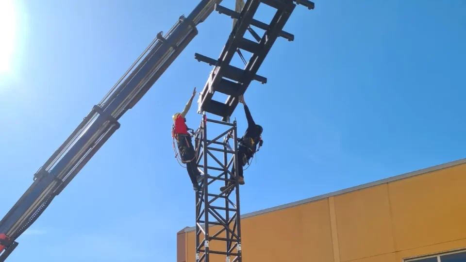 Montaje de una torre de delay LITEC HiPe Q76 de acero con grúa y dos técnicos de rigging en lo alto