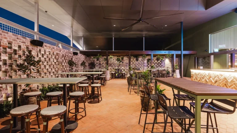 Zona exterior cubierta del Dakabin Hotel, en Queensland, con altavoces de superficie en la pared de ladrillo